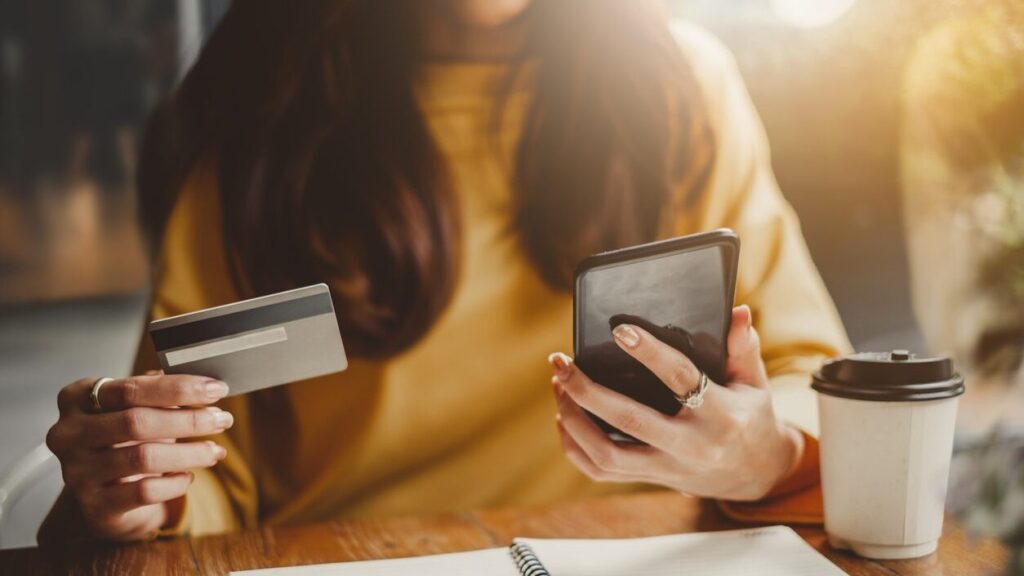 detailed view of a woman using credit card to pay on mobile phone