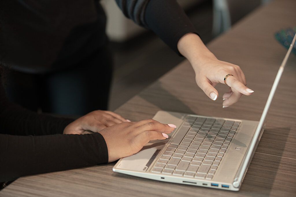 detail of two sets of hands looking at laptop
