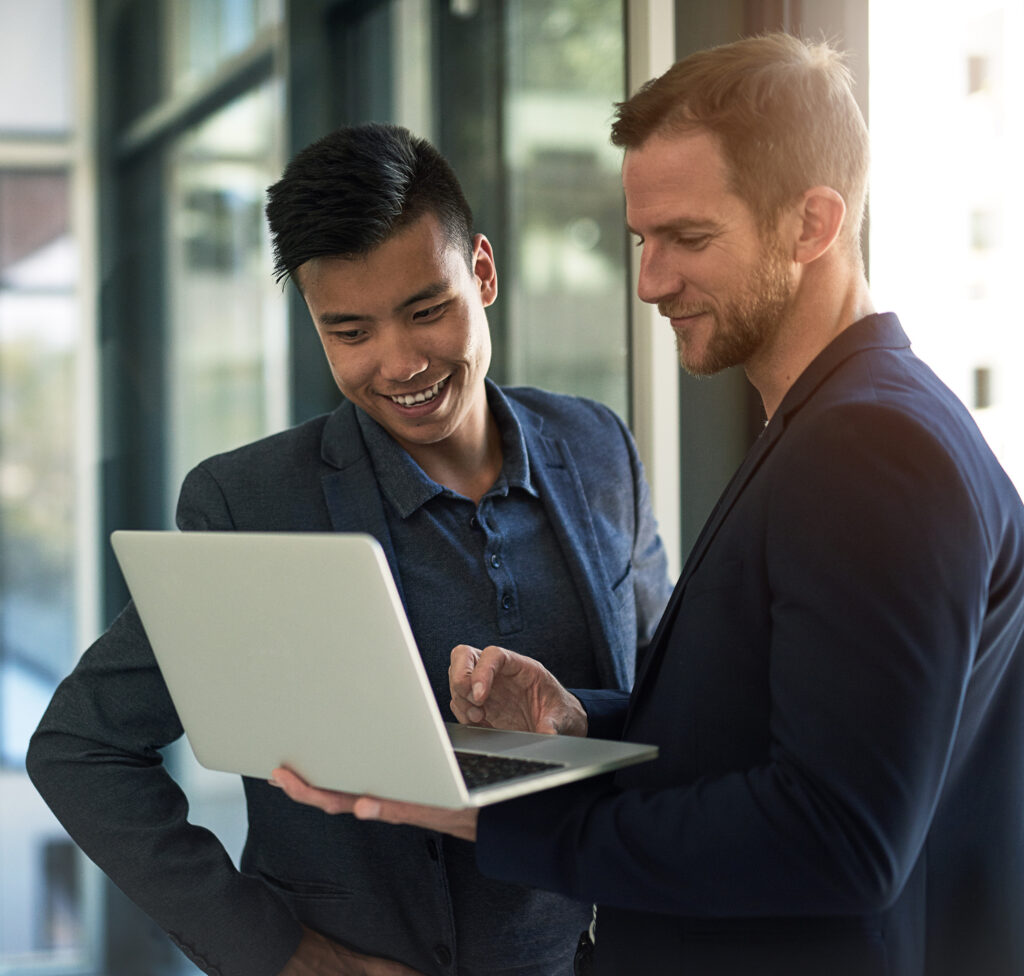 two businessmen discussing something on a laptop in an office