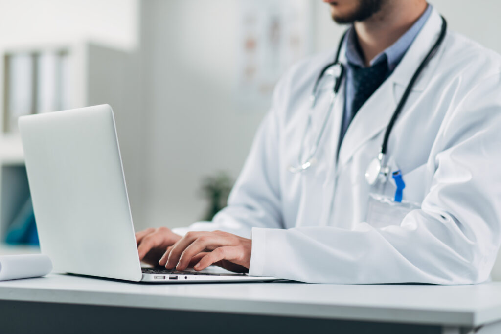 detail of young doctor working on laptop in his office