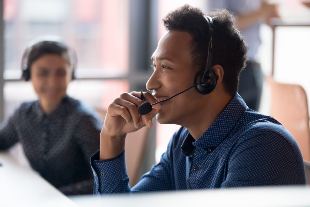 Smiling young businessman call center agent wearing a wireless headset