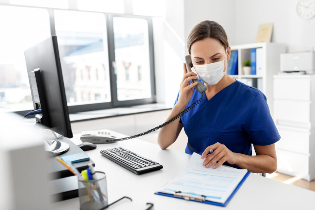 female nurse wearing safety protective mask filling out paperwork