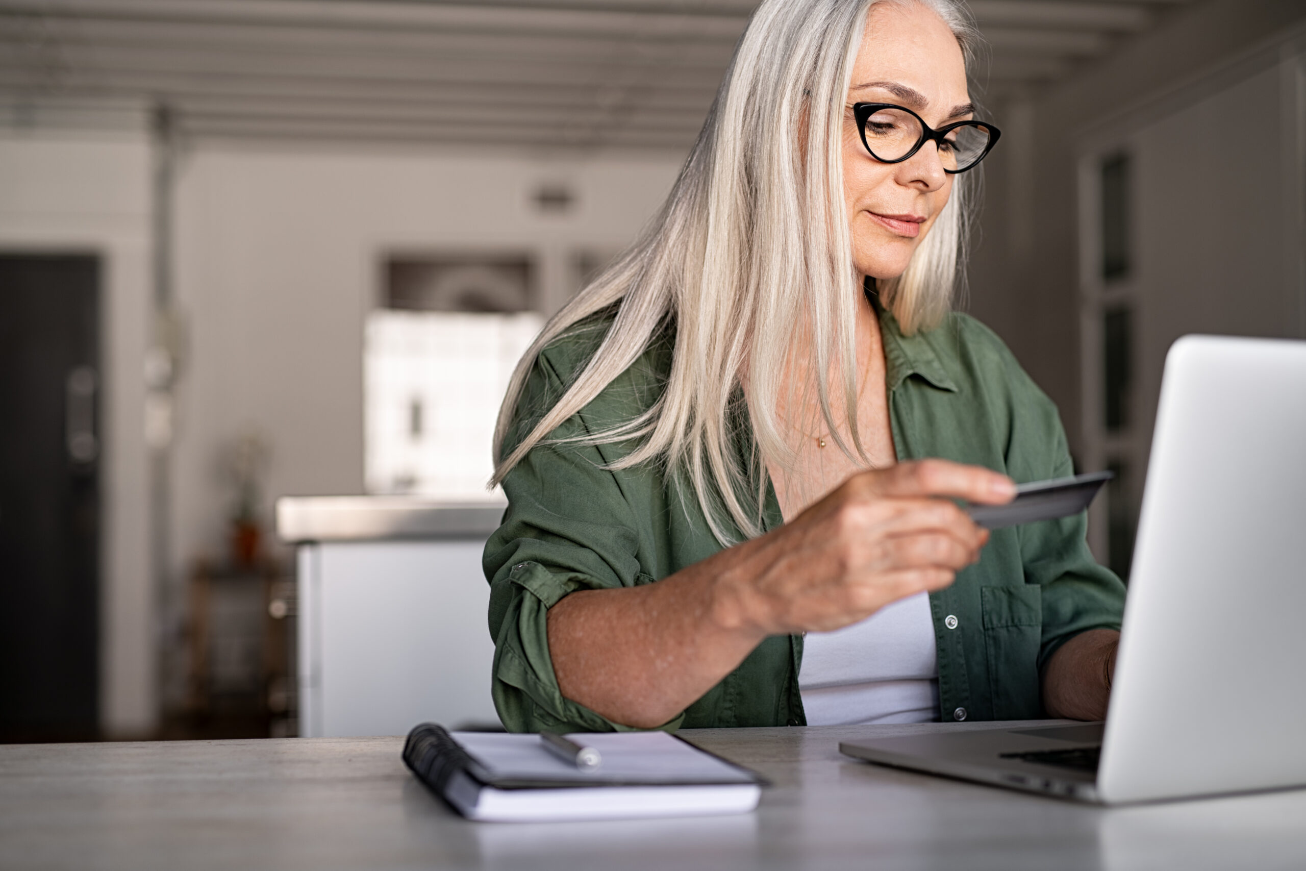 A woman with a credit card in sitting at a laptop