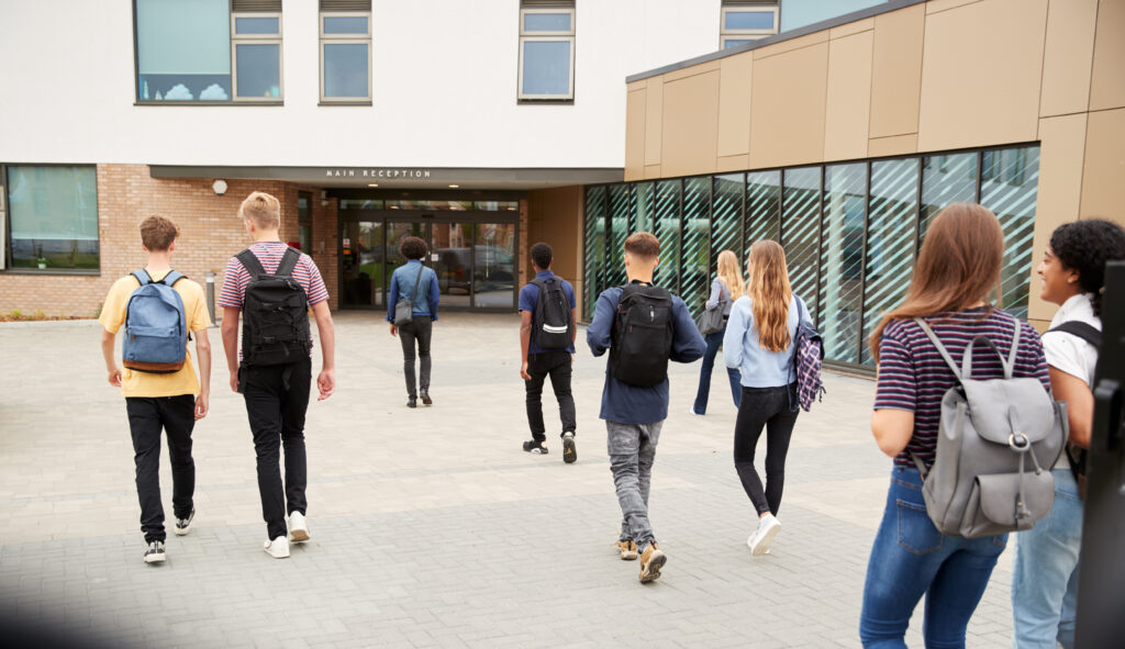 Several teenage students walking in front of a school building